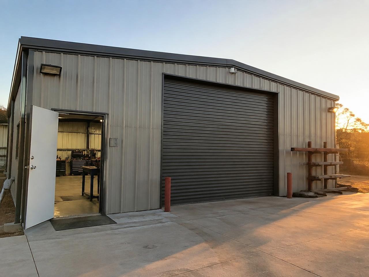 Enclosed metal workshop building with a walk-in door and a large roll-up door — illustrative image